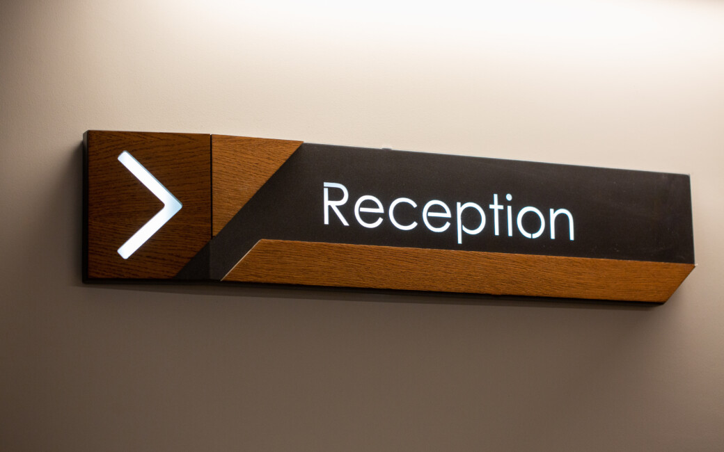 The,Reception,Sign,With,Direction,Arrow,On,The,Wall